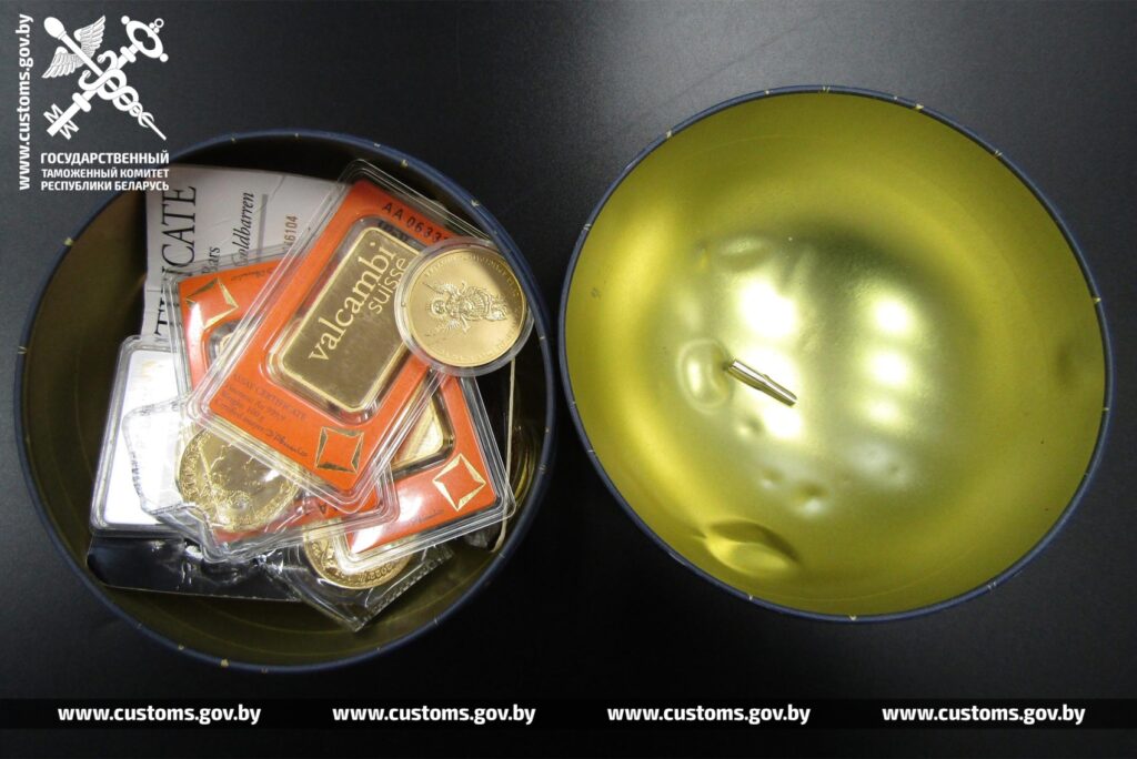 Золотые слитки и монеты внутри металлической коробки, раскрытой при таможенном досмотре.