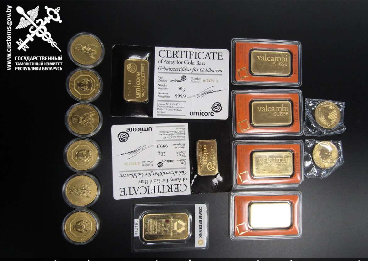 Разложенные на столе золотые слитки и монеты с сертификатами, изъятые таможней Беларуси.