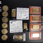 Разложенные на столе золотые слитки и монеты с сертификатами, изъятые таможней Беларуси.