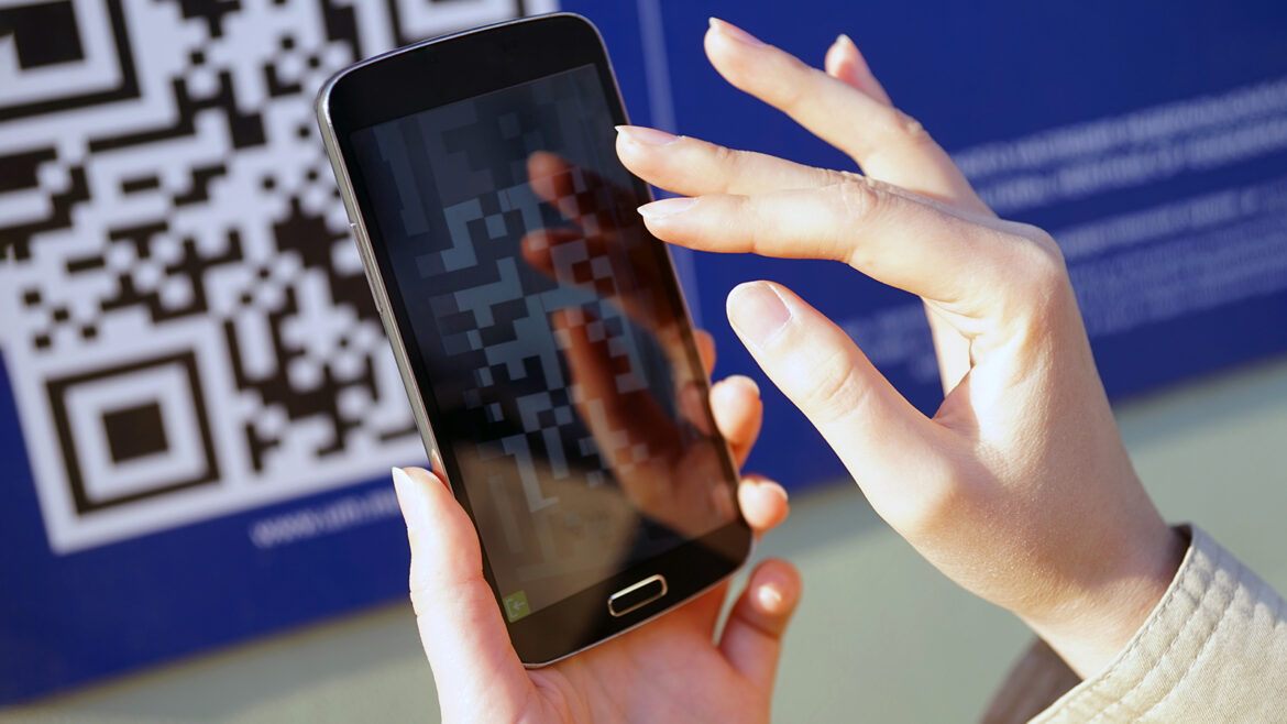 Смартфон с QR-кодом в руках человека – иллюстрация системы прослеживаемости товаров и цифрового контроля