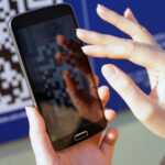 Смартфон с QR-кодом в руках человека – иллюстрация системы прослеживаемости товаров и цифрового контроля