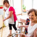 Надбавки в соцобслуживании – работник социальной службы помогает пожилой женщине по дому